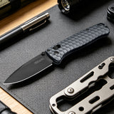 RBLACK S35VN Folding knife with textured handle on a dark surface with another knife and pen in the background.